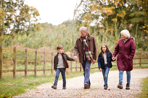 Grandparents With Grandchildren On Autumn Walk In Countryside Together