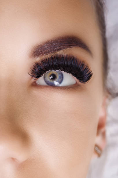 Eyelash Extension Procedure. Woman Eye with Long Eyelashes. Close up, selective focus. Hollywood, russian volume Eyelash Extension Procedure. Woman Eye with Long Eyelashes. Lashes. Close up, macro, selective focus russian culture audio stock pictures, royalty-free photos & images