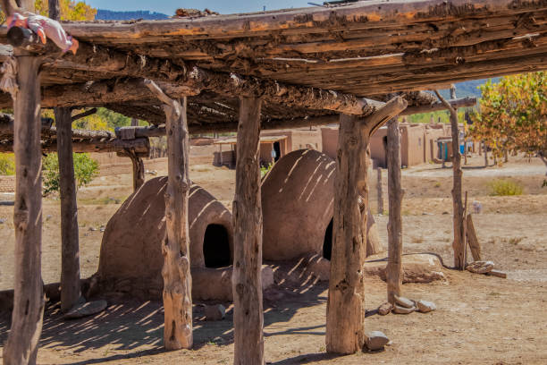 Two hornos-traditional earthen ovens- underneath a drying rack with a childs doll left on the corner - Homes of the Ute Pueblo in Taos New Mexico in the background - shallow focus Two hornos-traditional earthen ovens- underneath a drying rack with a childs doll left on the corner - Homes of the Ute Pueblo in Taos New Mexico in the background - shallow focus adobe oven stock pictures, royalty-free photos & images