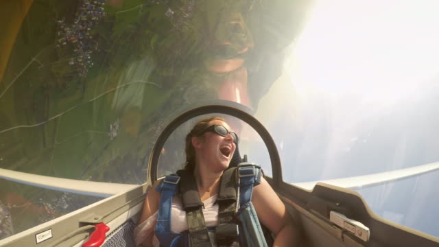 Wide locked down shot of a young female passenger in the back of the looping glider laughing while having fun. Shot in Slovenia.