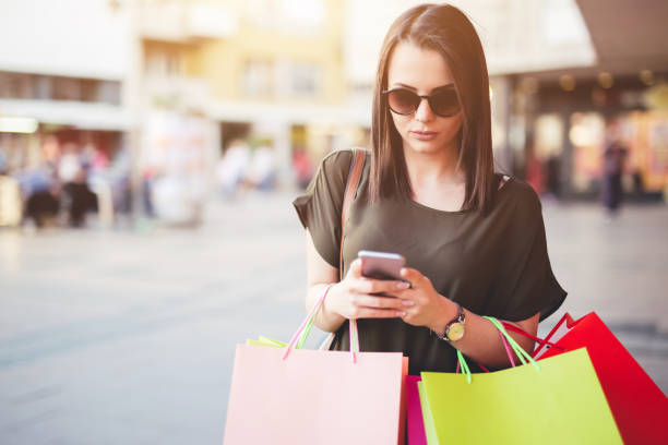 istock Young woman walking after shopping and using a mobile phone. 1065463170