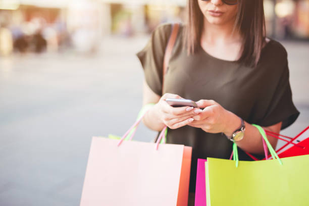 istock Young woman walking after shopping and using a mobile phone. 1065463330