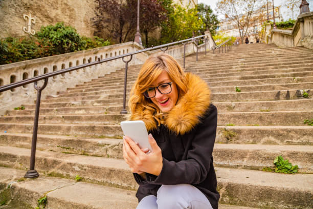 istock Cute smiley girl using cellphone in urban surroundings. 1065464564