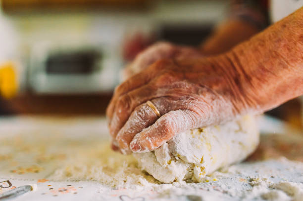 detail of old italian lady's hands making freh raw home made italian pasta in kitchen the old traditional way stock photo