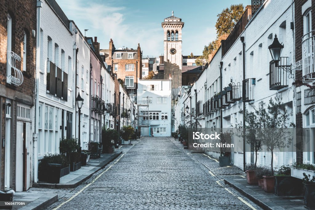 Exclusive mews in London Exclusive mews with small houses on the end tower of church London - England Stock Photo