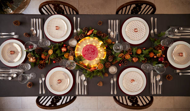 Christmas table setting with baubles arranged on plates and green and red table decorations, overhead view