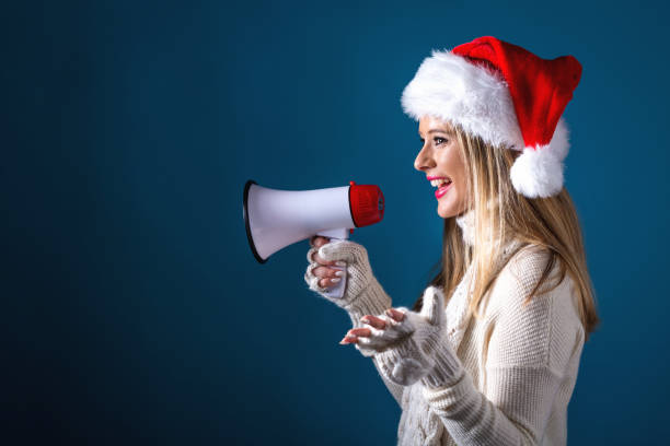 istock Young woman with santa hat holding a megaphone 1065479904