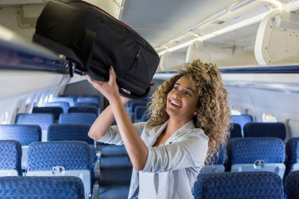 istock A young woman lifts up her baggage into overhead storage on a plane 1065483414