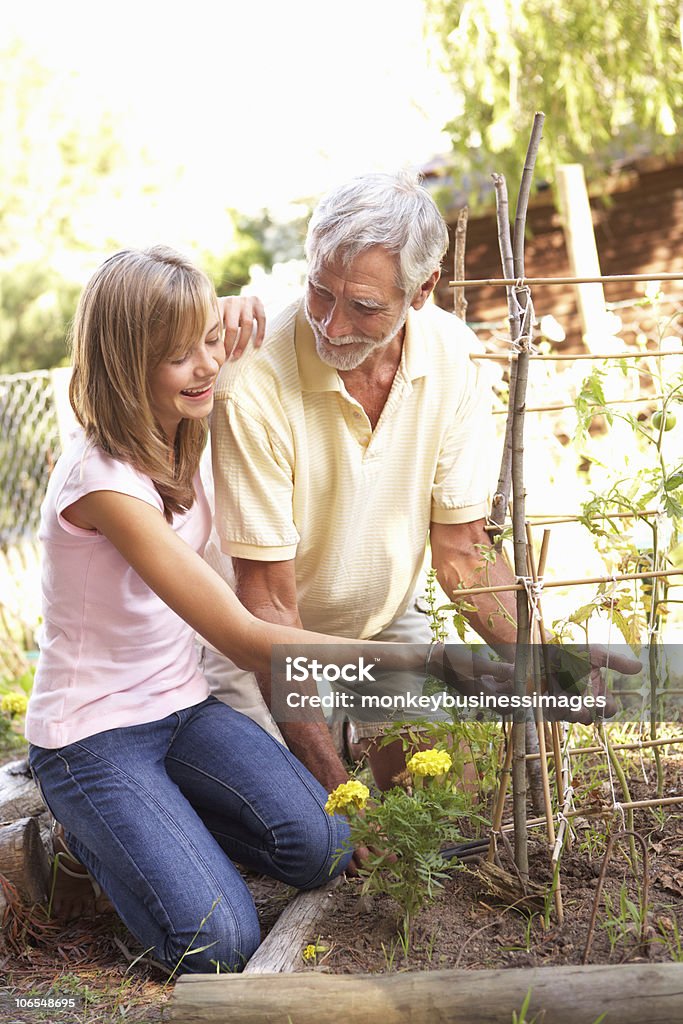 Teenage Granddaughter y abuelo descansar en el jardín - Foto de stock de 70-79 años libre de derechos