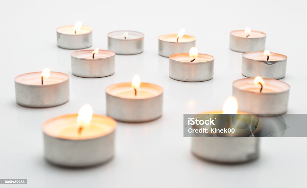 Burning paraffin candles, tealight, lies on a white background. Candle Stock Photo