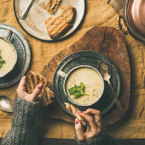 istock Celery cream soup and female hands with bread, square crop 1065495070