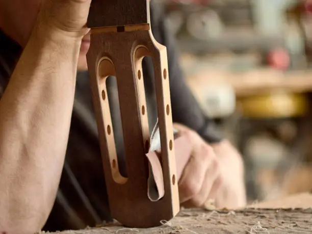 luthier grinds the head of the seven-string guitar.