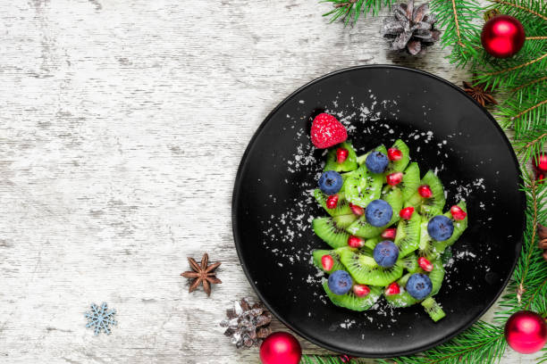 istock kiwi christmas tree with berries and coconut with fir tree branches and decorations over white wooden table 1065517054