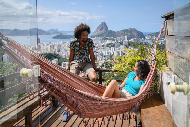 joven pareja en el balcón con vistas al rio en fondo - exotic location fotografías e imágenes de stock