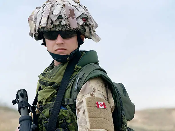Photo of A Canadian soldier in a camouflaged uniform with a gun