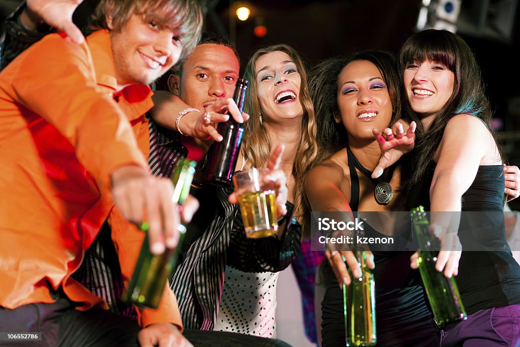 Group of diverse friends drinking alcohol in a nightclub  Group of friends - men and women of different ethnicity - having fun in a disco or nightclub Adult Stock Photo