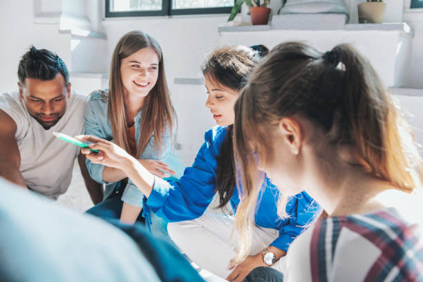 istock four young people sitting on floor discussing 1065536344