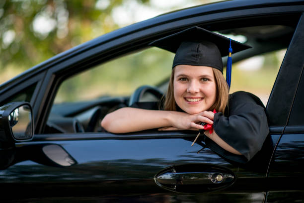 graduate sits in a new car she has been given - university graduation car student imagens e fotografias de stock