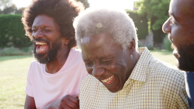 Senior black man laughing with his two adult sons, close up