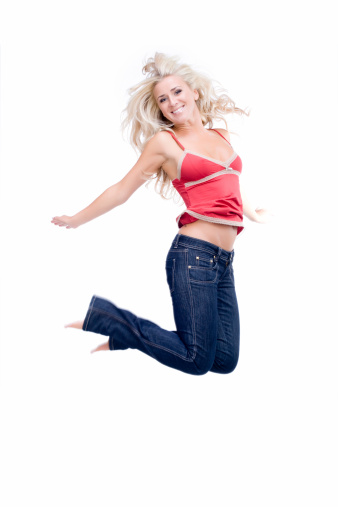 Full length studio shot of pretty young woman jumping in air. Over white background