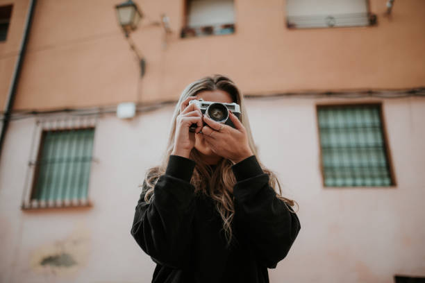 istock Young woman taking a picture with a vintage camera 1065544442