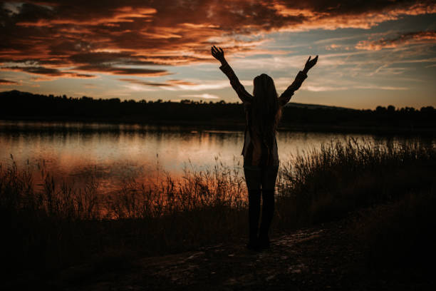 istock Young woman with arms raised by lake 1065548736