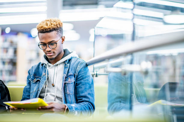 istock University student focusing on his studies in a library 1065557298