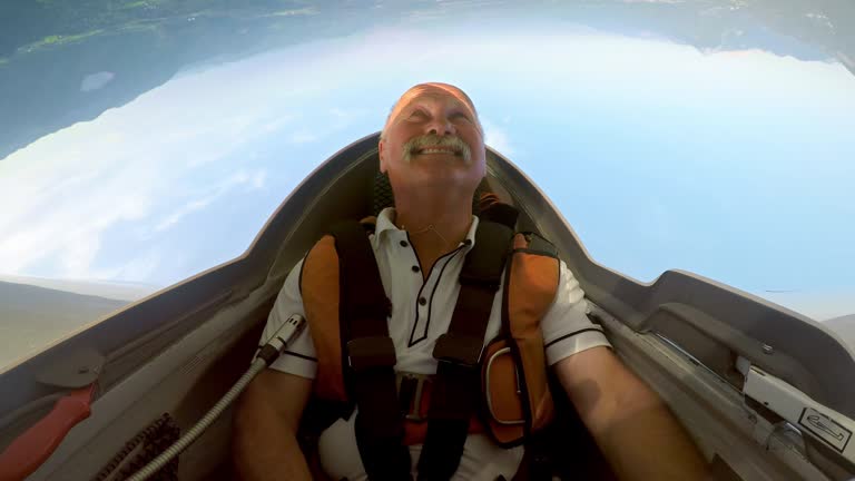 Wide locked down shot of a male pilot doing stunts in his glider above the sunny landscape. Shot in Slovenia.