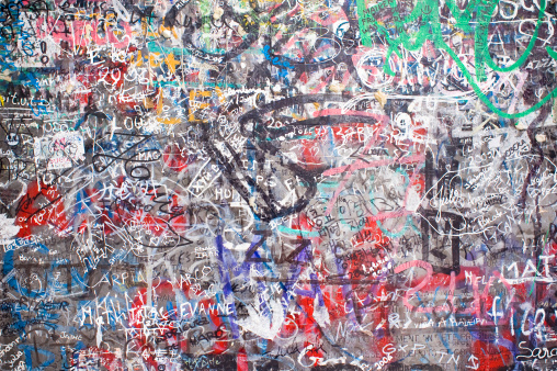 Color image of a wall that has graffiti designs on it.