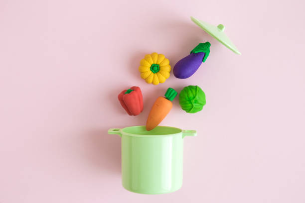 istock Vegetables falling in kitchen cooking casserole pot abstract isolated on rose. 1065573266