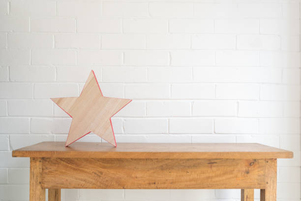 Wooden star on oak side table against painted brick wall with copy space - minimal festive season concept