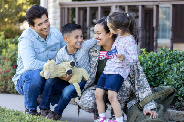 Happy woman is reunited with family after military assignment Smiling mid adult female soldier enjoys time with her little family upon her return from deployment. proud army mom stock pictures, royalty-free photos & images