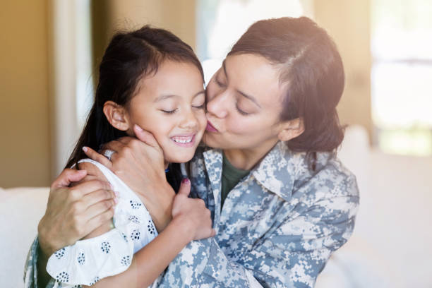 Happy army mom kisses young daughter Relieved military mom gives her adorable daughter a kiss on the cheek. The woman has just returned from a long military assignment. proud army mom stock pictures, royalty-free photos & images