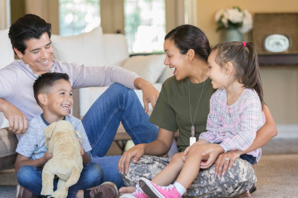 Army mom is reunited with her family Excited mid adult female soldier enjoys time with her family upon her return home from military assignment. proud army mom stock pictures, royalty-free photos & images
