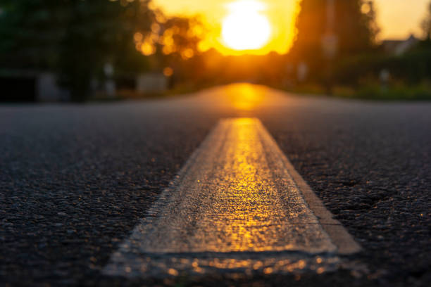 istock Close-up of a road, sun setting on the horizon 1065595546