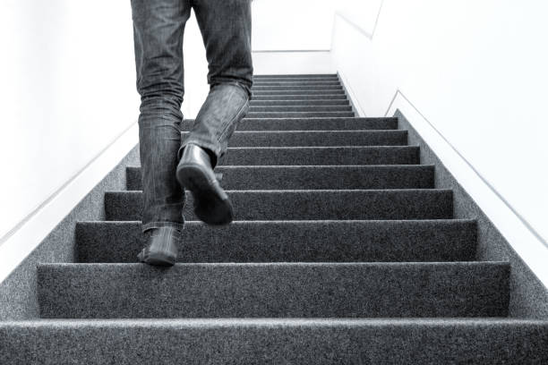 low angle picture of man walking upstairs on indoors - upstairs imagens e fotografias de stock