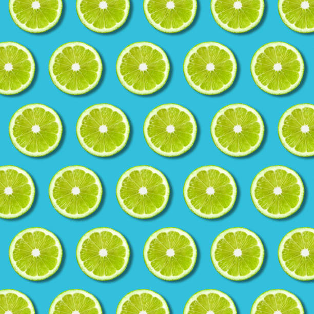 patrón de rodajas de limón verde sobre fondo turquesa vibrante - limones verdes fotografías e imágenes de stock