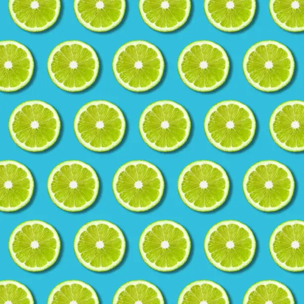 Photo of Green lime slices pattern on vibrant turquoise background