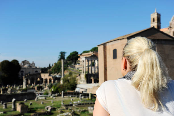 la giovane donna bionda guarda il panorama ai fori imperiali (fori imperiali) a roma. - caesar emperor rome stone foto e immagini stock