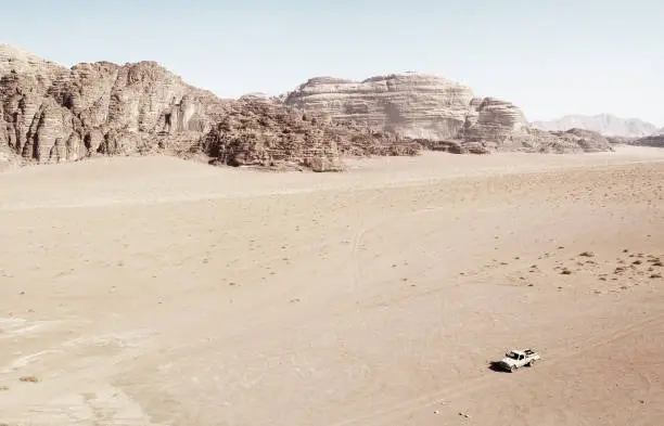 A car crosses a lonely stretch of the Wadi-Rum desert