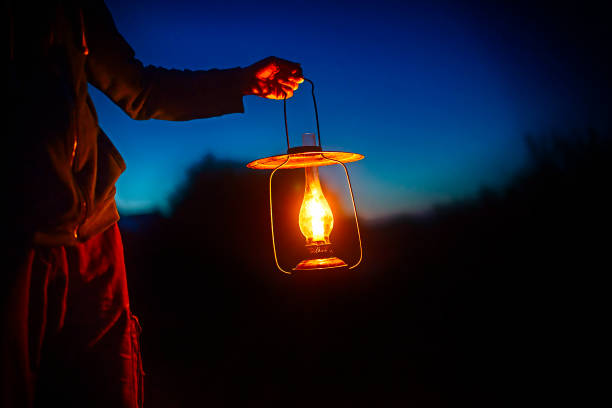 hand holds a large old lamp in the dark. man holding the vintage lamp with a candle outside. Copy space for your text lantern photos stock pictures, royalty-free photos & images
