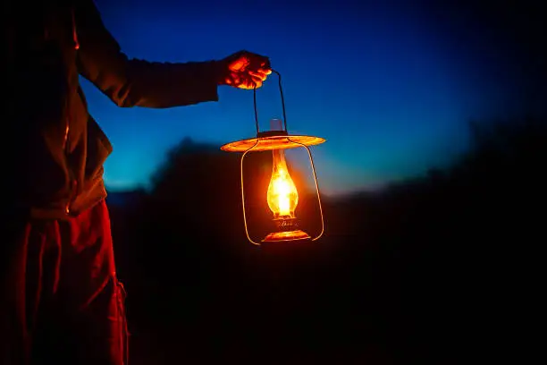 man holding the vintage lamp with a candle outside. Copy space for your text