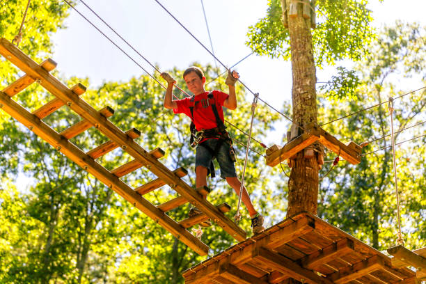 istock boy climbing in a high wire park above the ground. ziplining. 1065624108