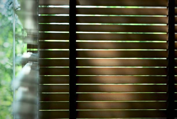 istock Evening sun light outside wooden window blinds, sunshine and shadow on window blind and Granite tile wall 1065633178