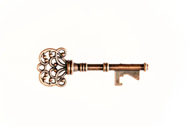 Side view of ornate brass skeleton key for door or lock on white.
