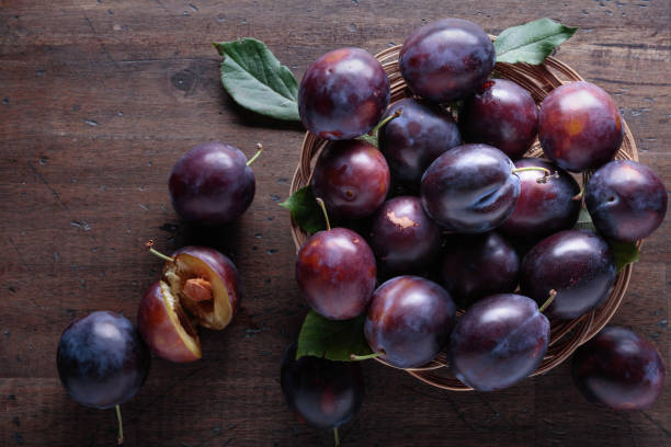 istock Ripe juicy plums on a wooden background. 1065633952