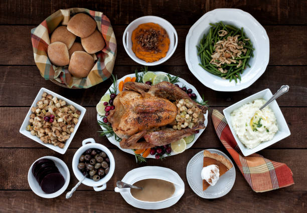 Thanksgiving Turkey Dinner Thanksgiving turkey dinner on an old wood background with mashed potatoes, sweet potatoes, gravy, stuffing, green beans, buns, olives, cranberry sauce and pumpkin pie dessert stuffing food photos stock pictures, royalty-free photos & images