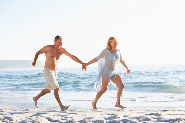 istock Senior Couple On Holiday Running Along Sandy Beach 106564528