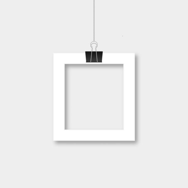 Realistic isolated paper photo frame hanging by binder clips. Retro vintage style mockup. Vector illustration. Template with blank area for your picture. Realistic isolated paper photo frame hanging by binder clips. Retro vintage style mockup. Vector illustration. Easy to edit template with blank area for your picture. photos hanging string stock illustrations