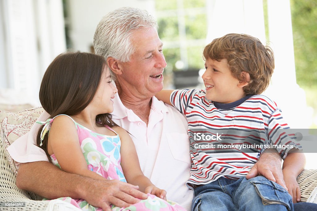 Abuelo y nietos relajante en silla - Foto de stock de 30-39 años libre de derechos